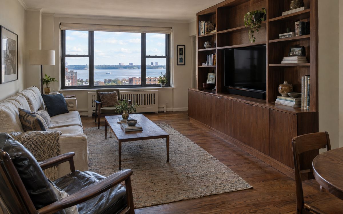 A walnut built-in media wall in a Riverdale co-op living room with a Hudson River view, design concept