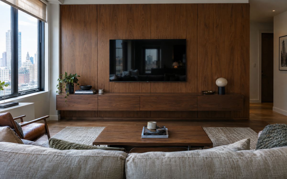 A walnut media wall with the TV at seated eye level above a floating console, design concept