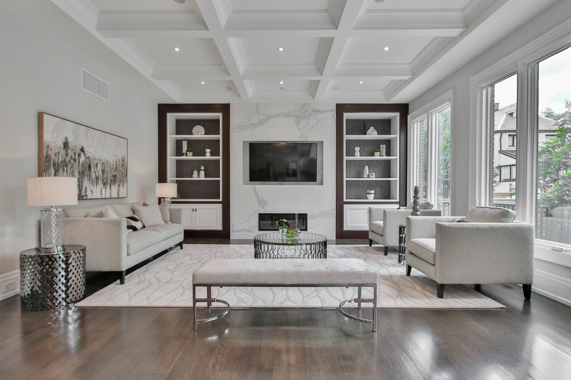A coffered living room with dark built-in shelving around a marble fireplace